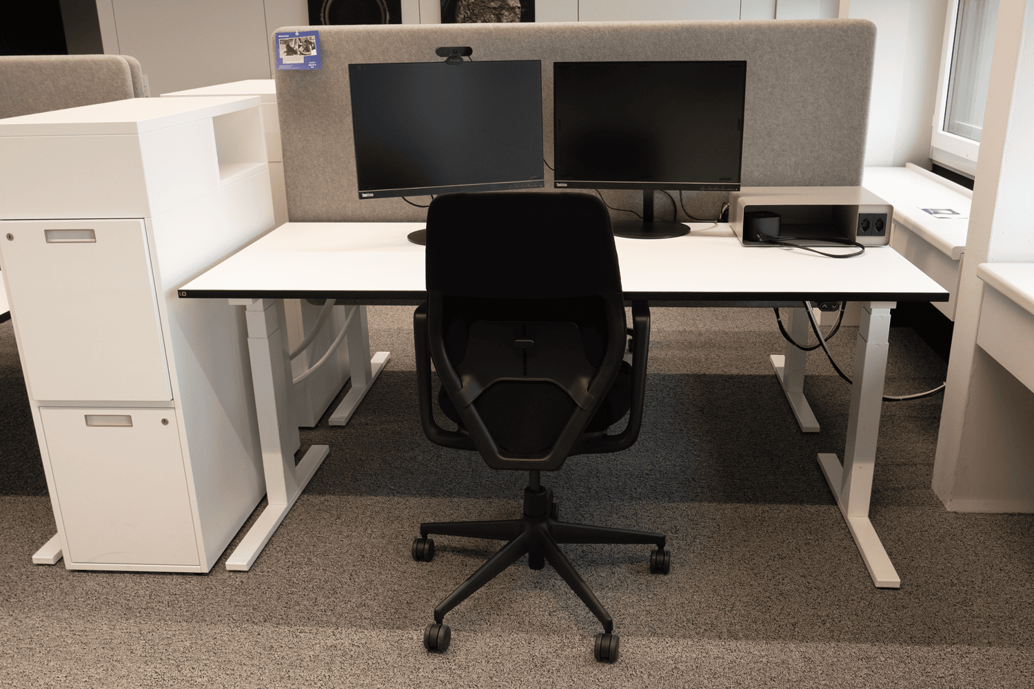 Ein ergonomisch eingerichteter Arbeitsplatz mit B&uuml;rostuhl, zwei Bildschirmen und Stehtisch